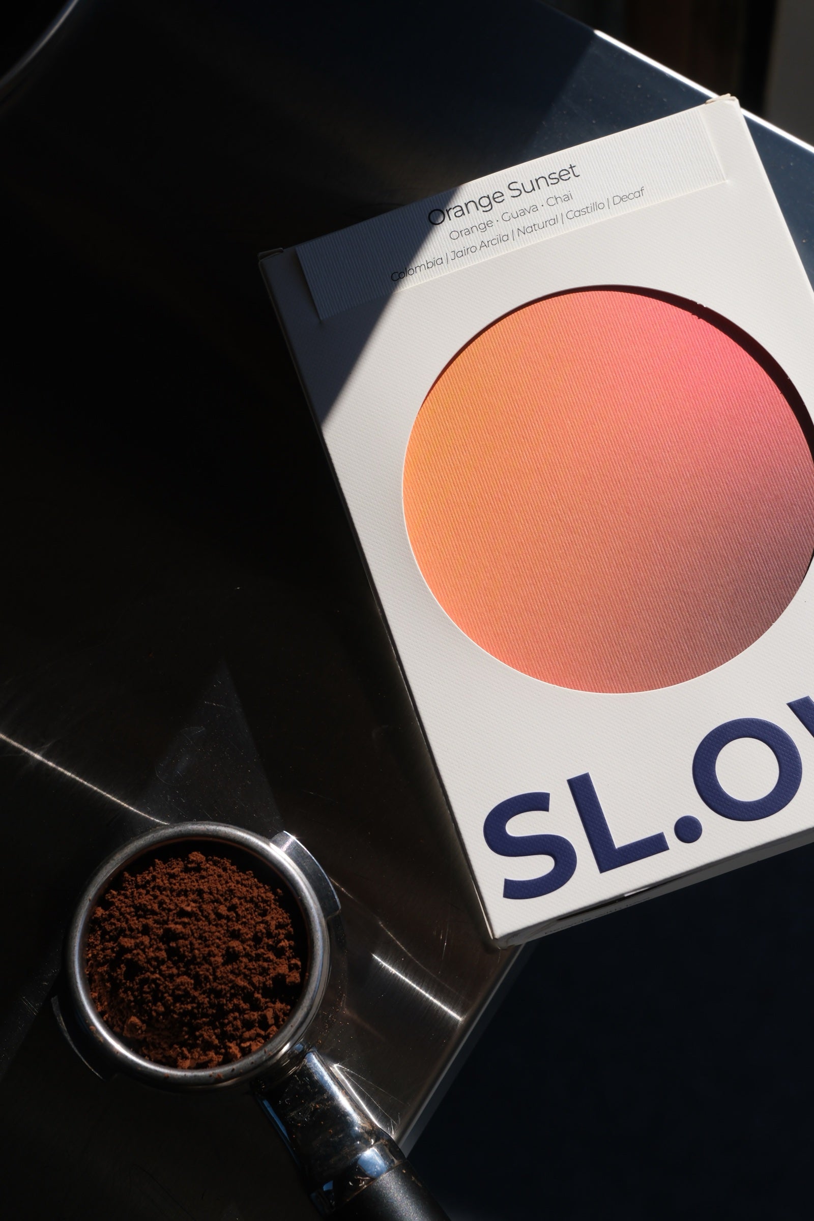 Orange Sunset Colombian Decaf — package with portafilter of grounds