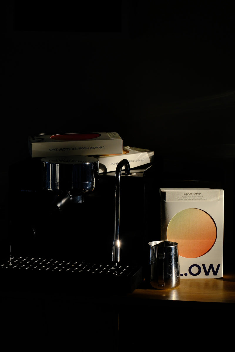 Apricot Affair box beside an espresso machine and grinder in low morning light
