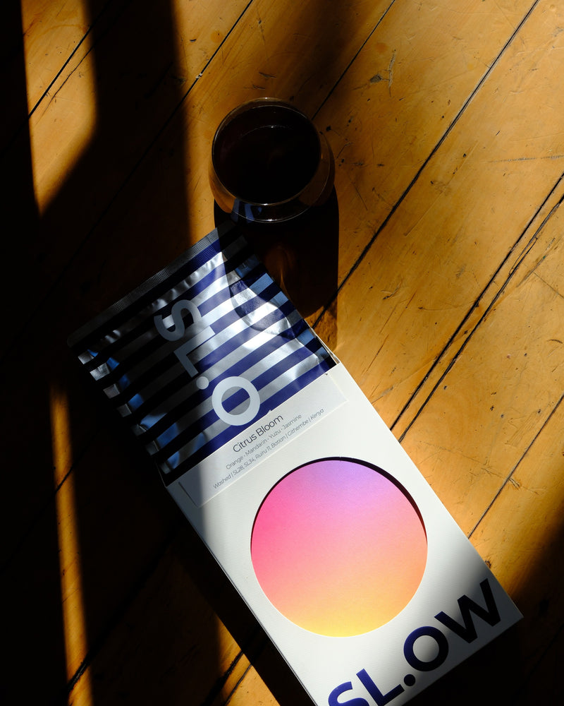Citrus Bloom 200g box with black coffee in morning light