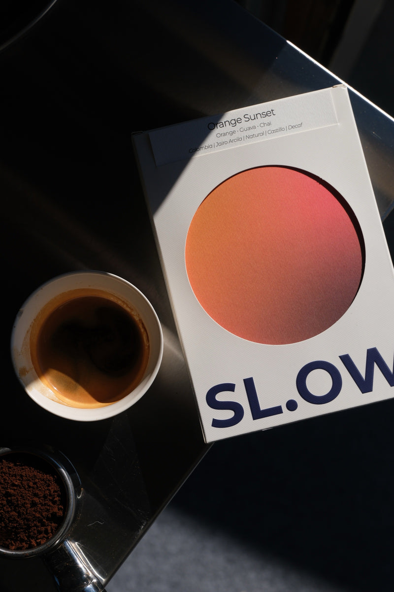 Orange Sunset Colombian Decaf — package with cup of coffee