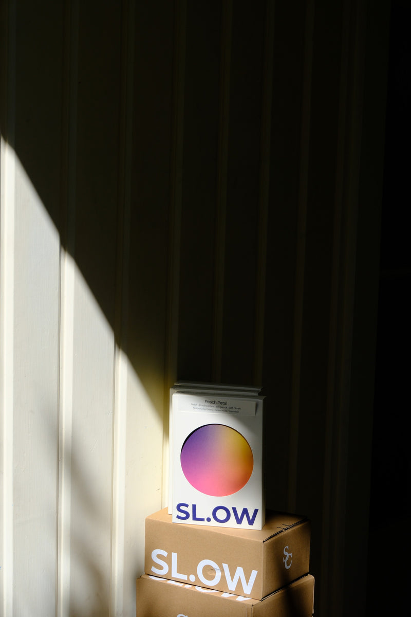Peach Petal box on stacked SL.OW shipping boxes in window light